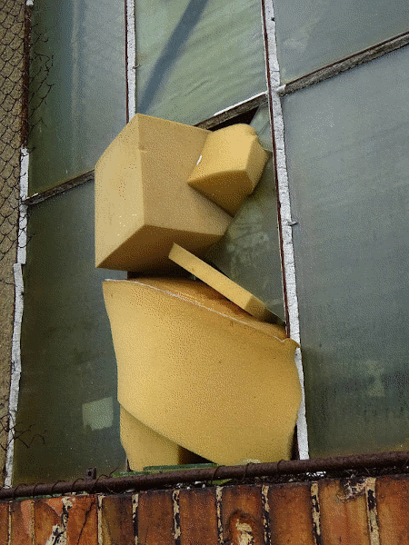 the shattered glass window in the old foam office factory building are stuffed with foam