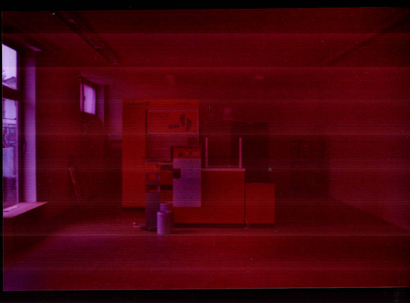 An abandoned post office. An empty counter stands alone in the room. Photography with old analogue film, scan lines.