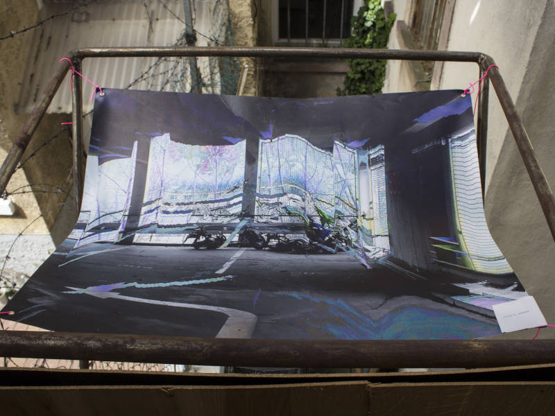 picture of a parking scenario with broken scooters, printed on pvc canvas, attached to an iron balcony structure at the second exhibition location in some backyard studio