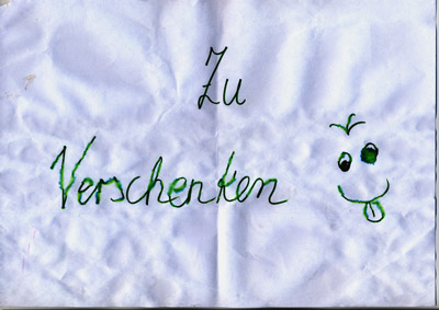 piece of paper with handwritten words “Zu Verschenken” (Give Away), and a cheeky smiley face